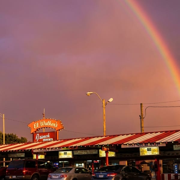 El Walker's Drive-In restaurant with a red and white striped awning under a vibrant rainbow.