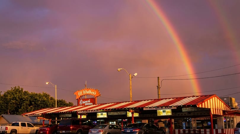 El Walker's Drive-In restaurant with a red and white striped awning under a vibrant rainbow.